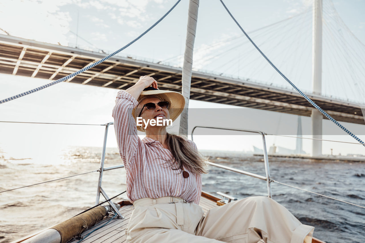 Senior woman sitting on boat against sea