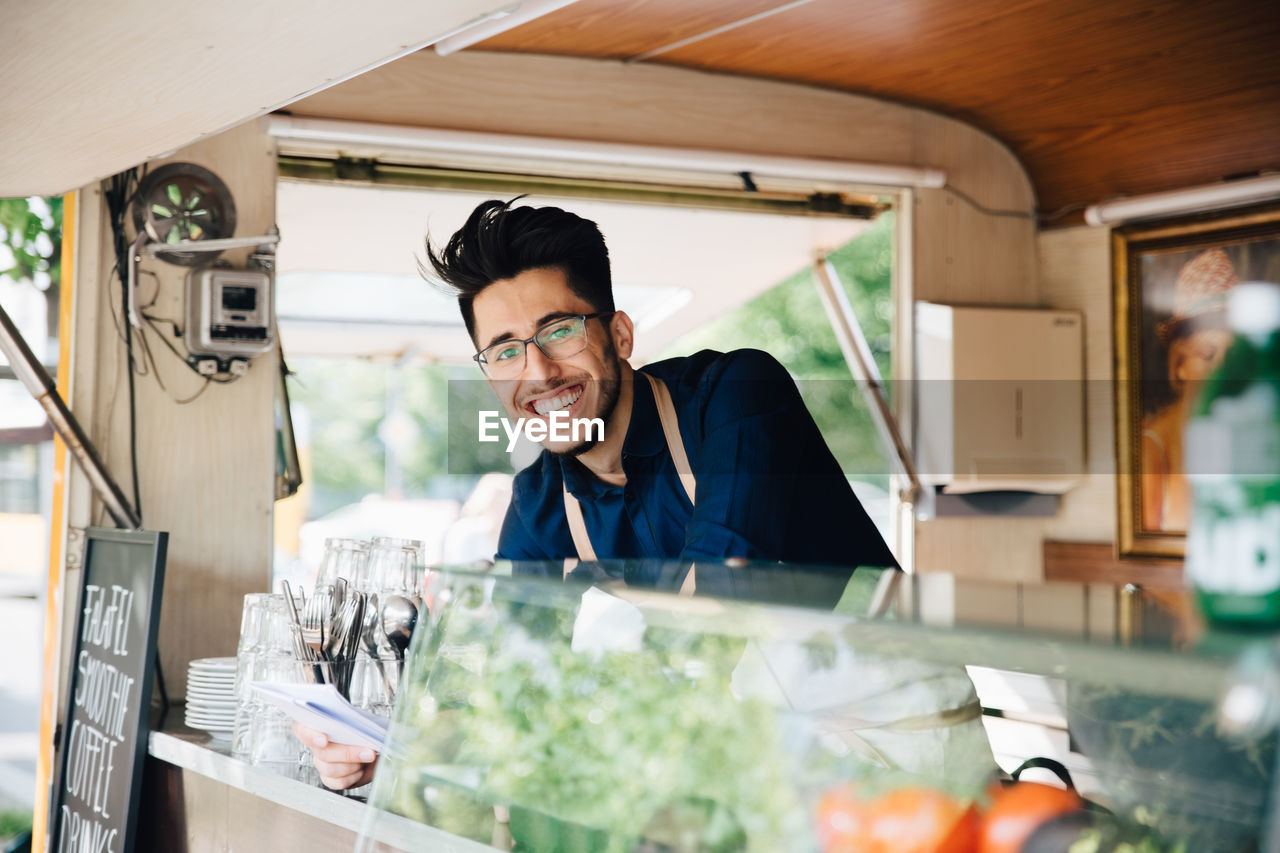 Portrait of happy young entrepreneur standing in food truck