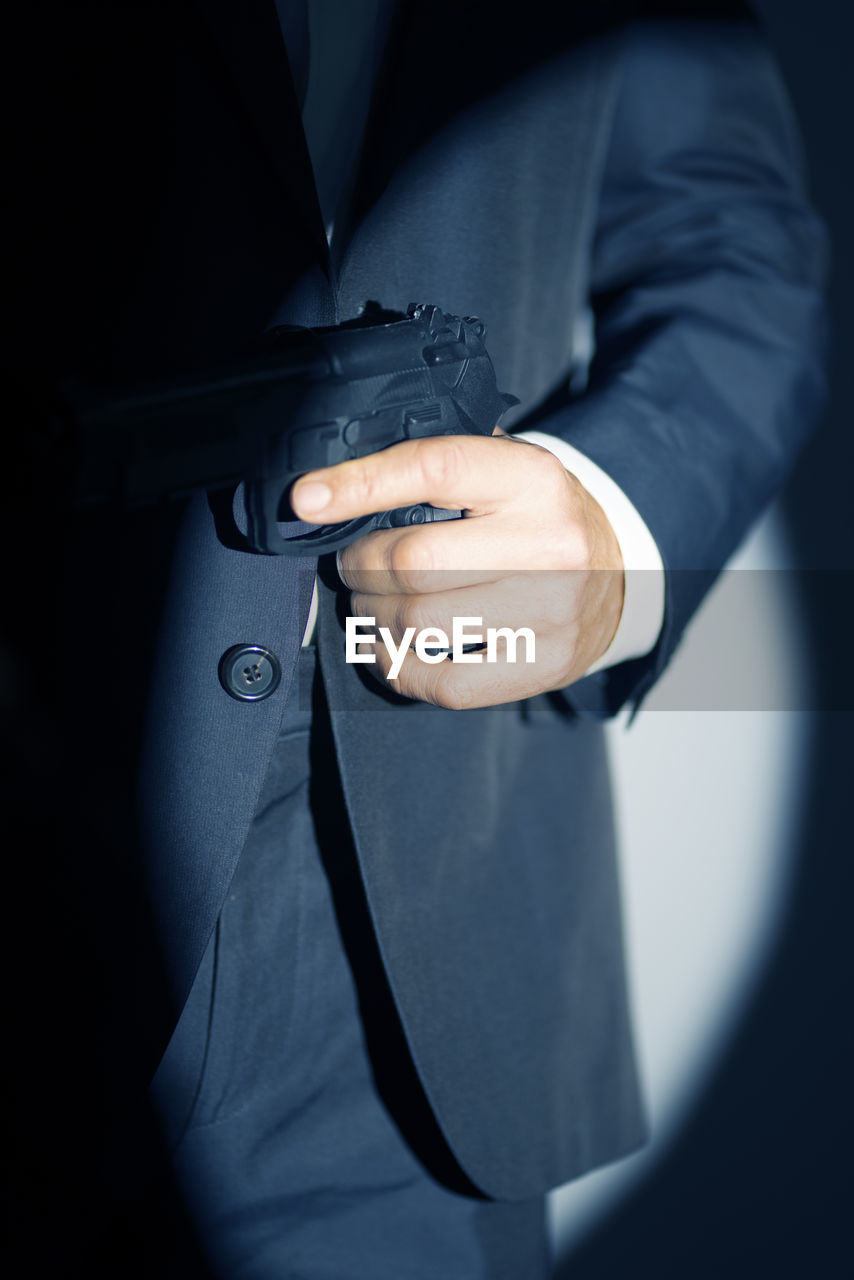 midsection of businessman holding hands against black background