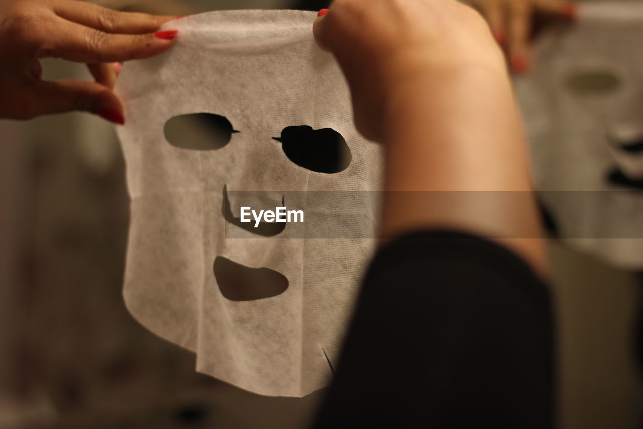 Cropped hands of woman using facial mask at home