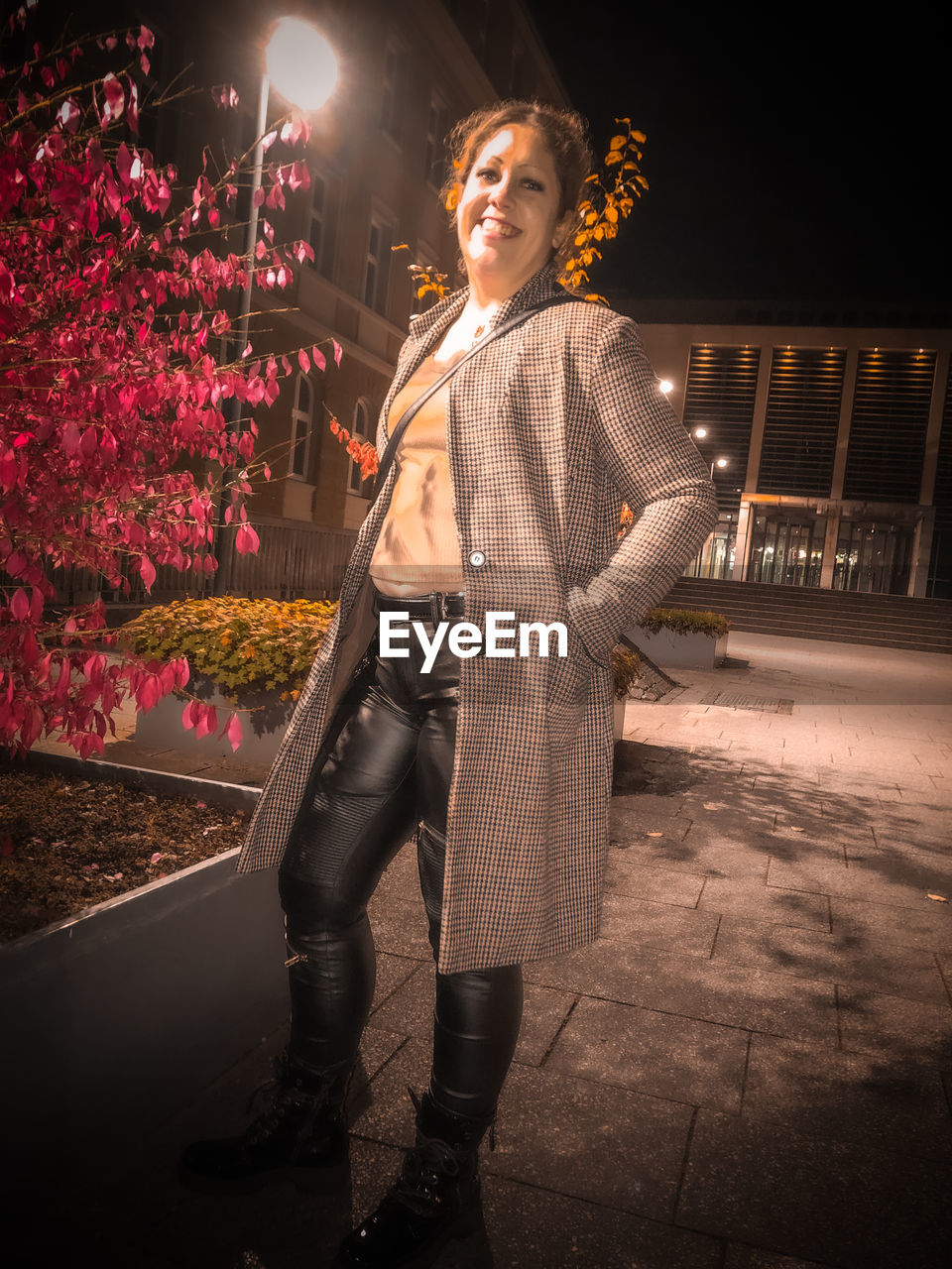 one person, night, adult, fashion, standing, young adult, illuminated, darkness, portrait, full length, women, clothing, architecture, smiling, emotion, city, arts culture and entertainment, nature, looking at camera, celebration, happiness, plant, performance art, casual clothing, street