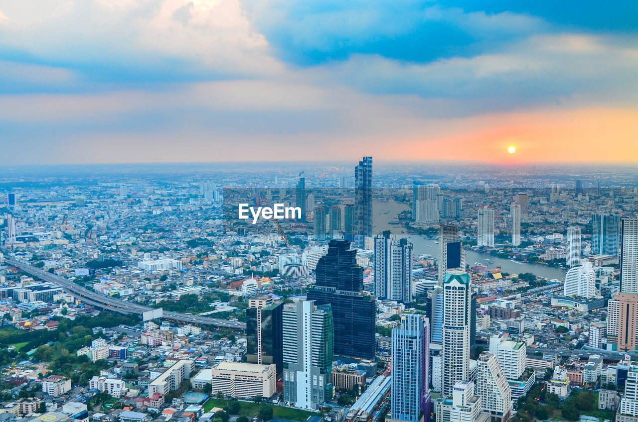 Aerial view of buildings in city against cloudy sky