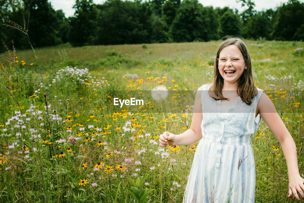 Girl laughing as she picks wild flowers in a field