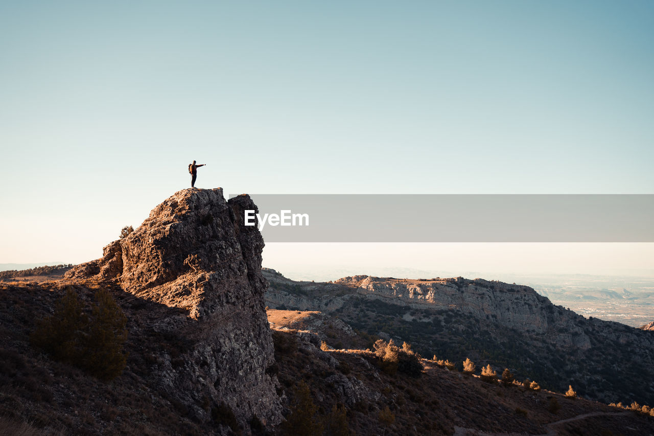 Man standing on cliff against clear sky