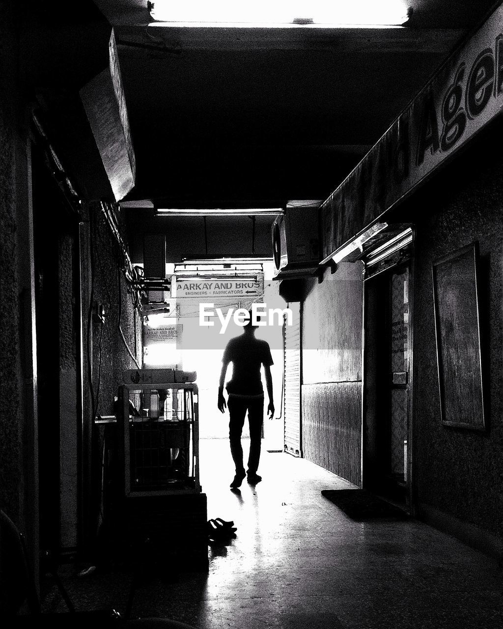 REAR VIEW OF SILHOUETTE MAN WALKING IN BUILDING