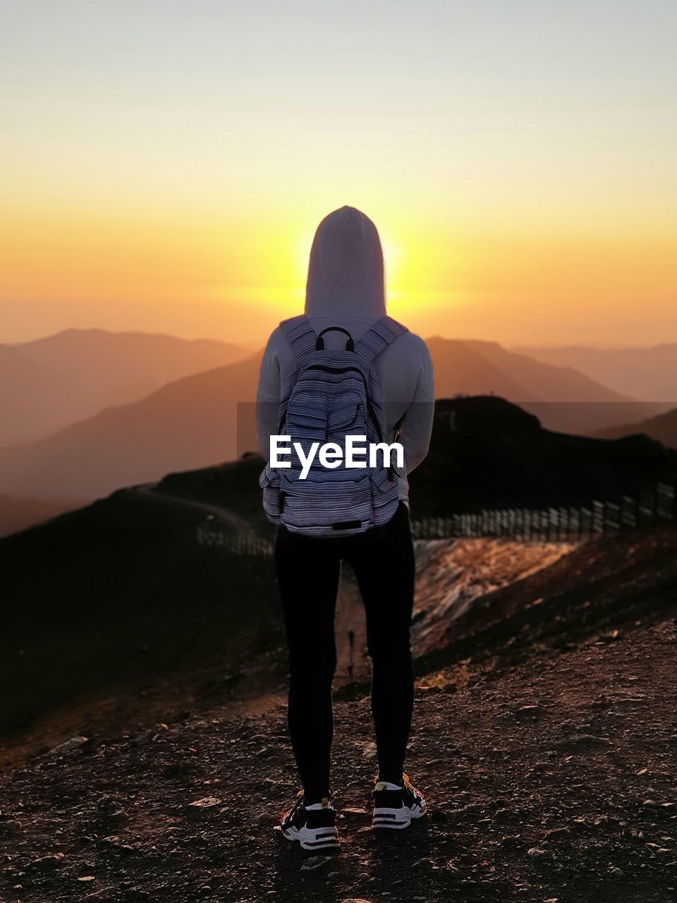 Rear view of woman standing on mountain during sunset