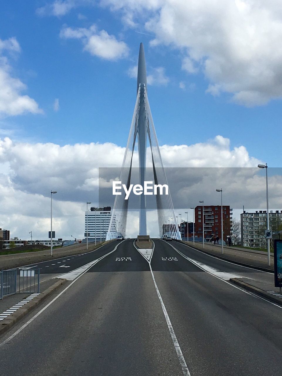 Low angle view of a road leading towards city against cloudy sky