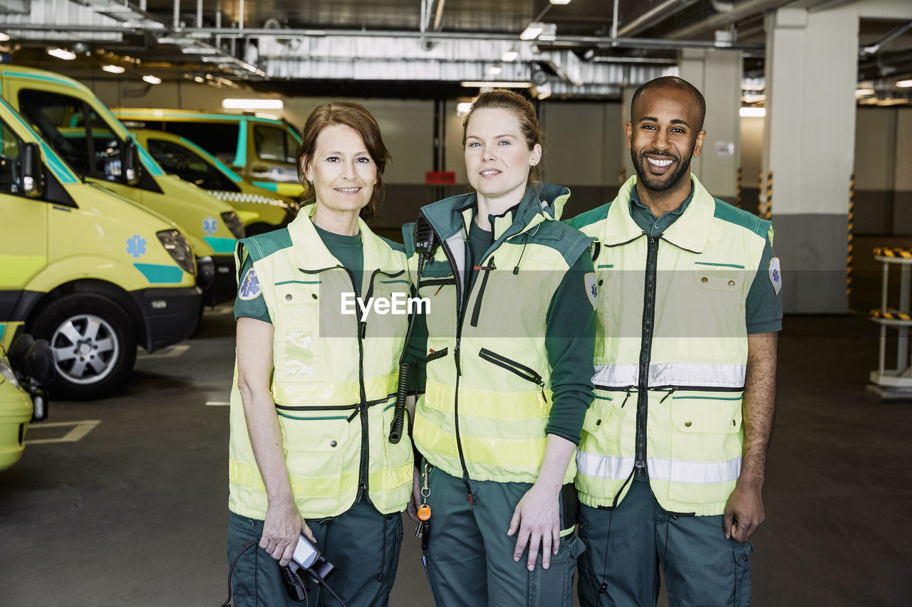 Portrait of confident paramedics standing against ambulance in parking lot