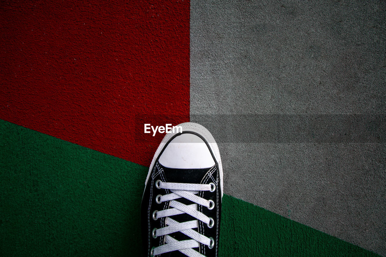 LOW SECTION OF PERSON STANDING ON TILED WALL