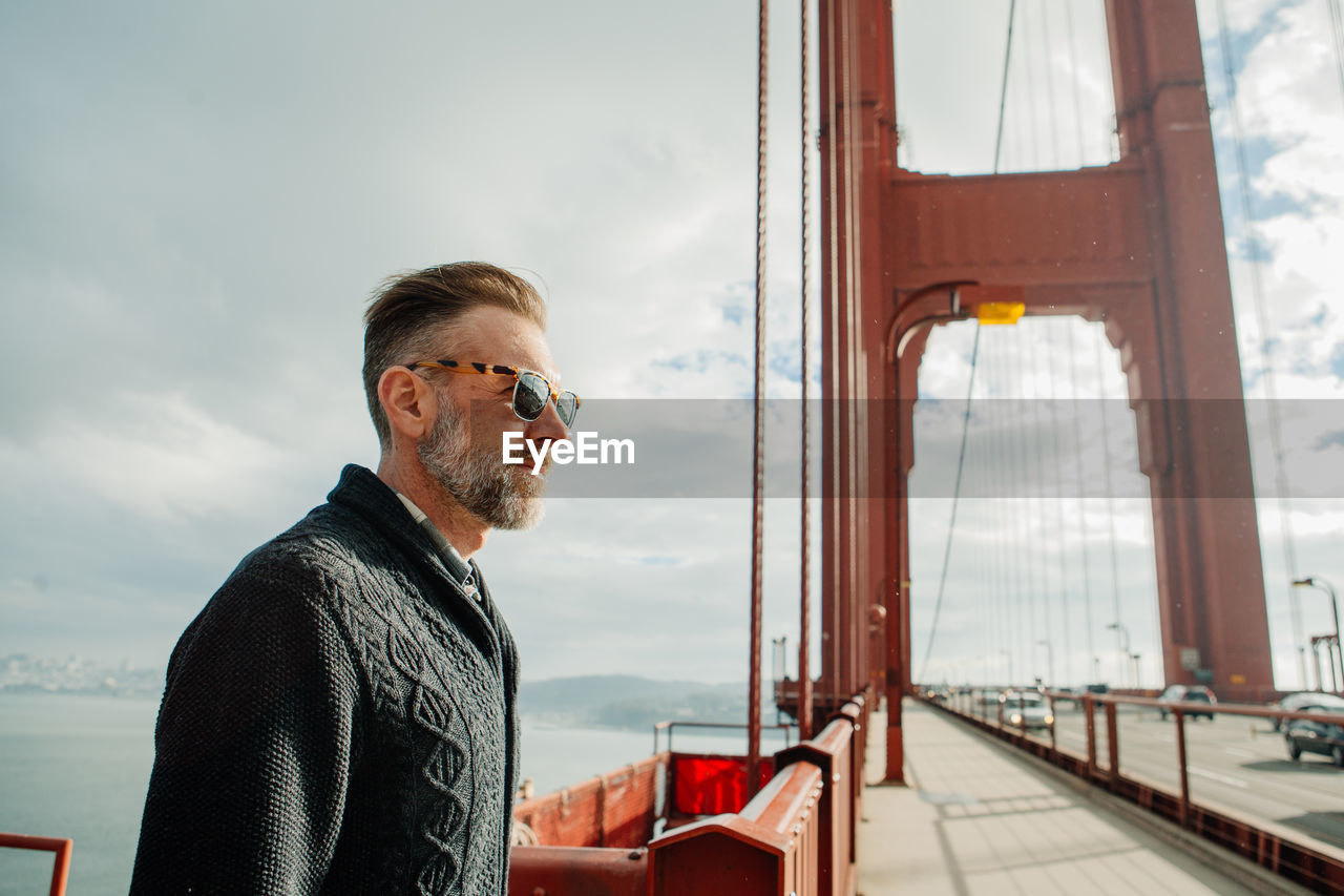 Profile portrait of adult man with beard standing on the golden gate bridge during cloudy weather