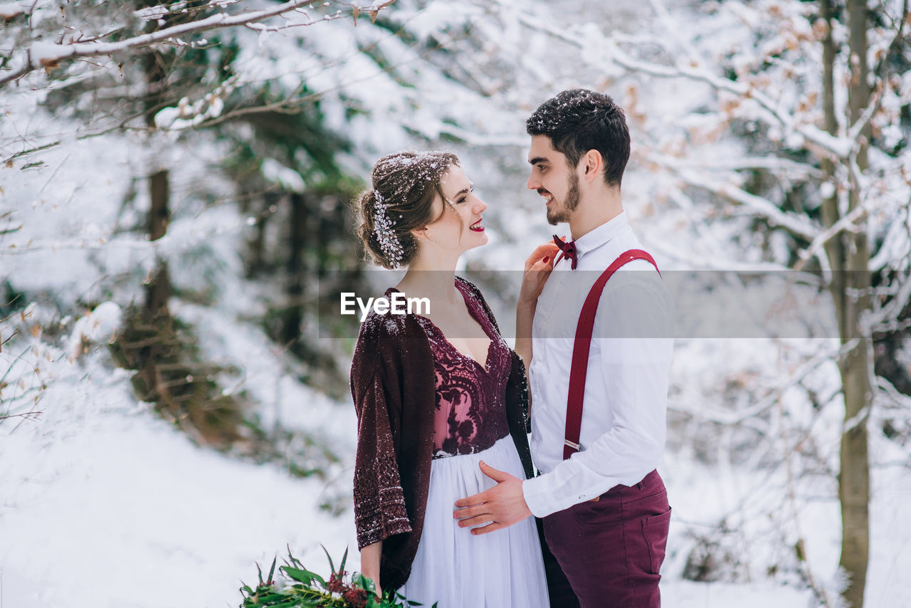 YOUNG COUPLE STANDING IN SNOW