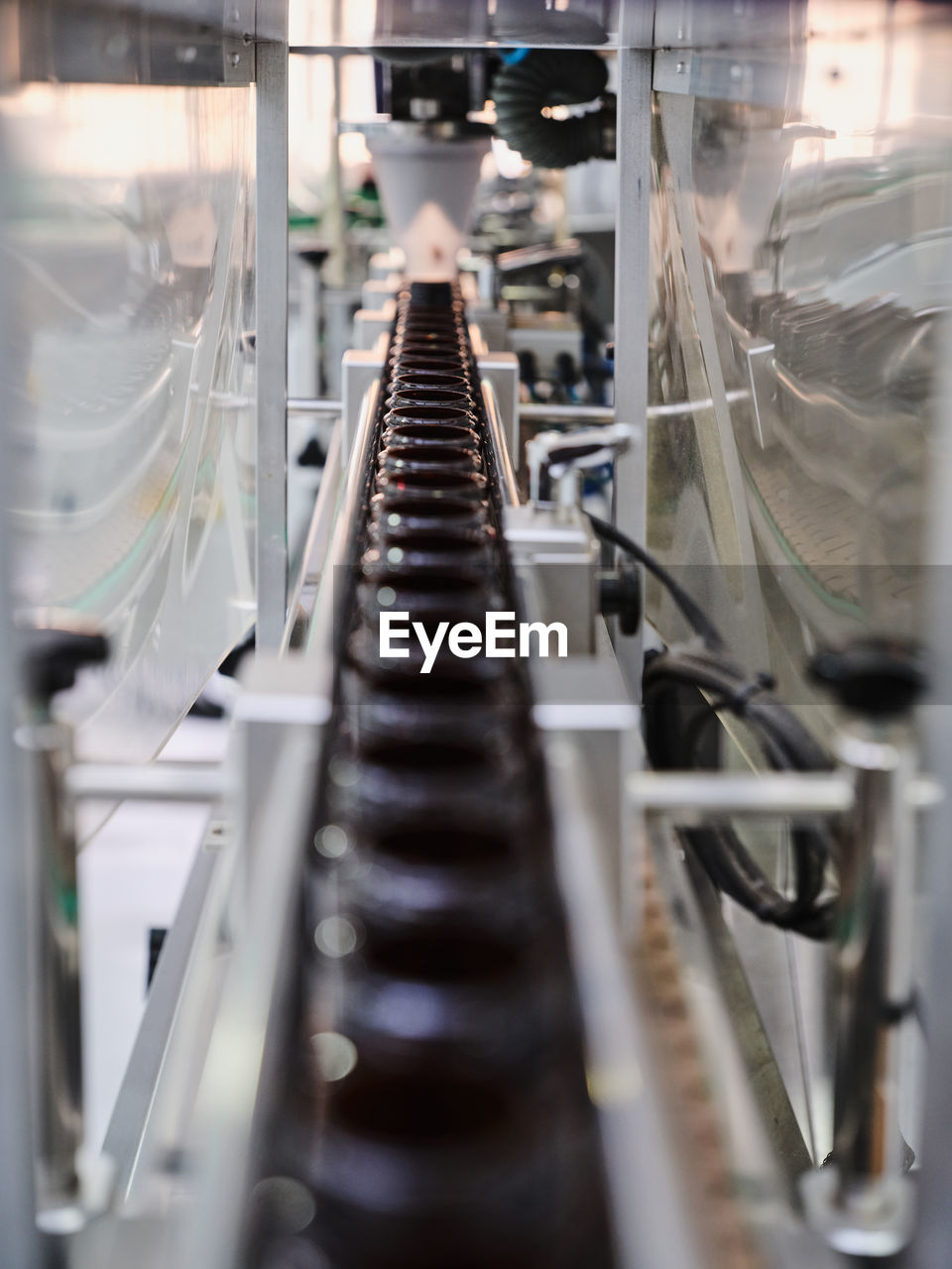 Row of plastic bottles on conveyor of filling machine at modern pharmaceutical manufacturing plant
