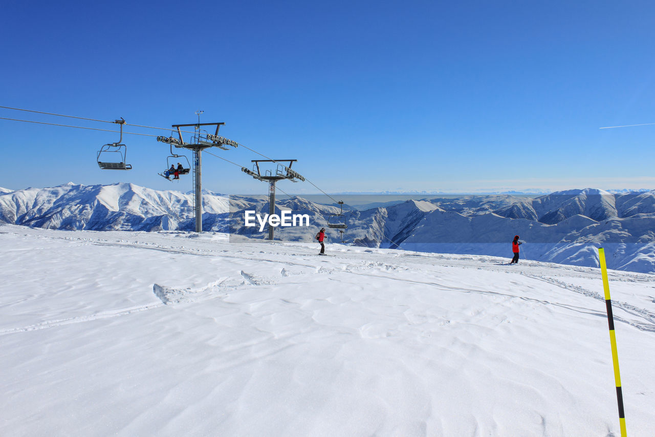 Chairlift and skiers at the ski resort. against the background of snow ridges and blue sky