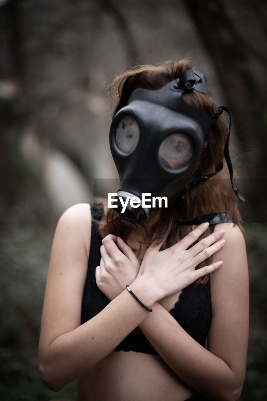 Woman wearing gas mask while covering chest