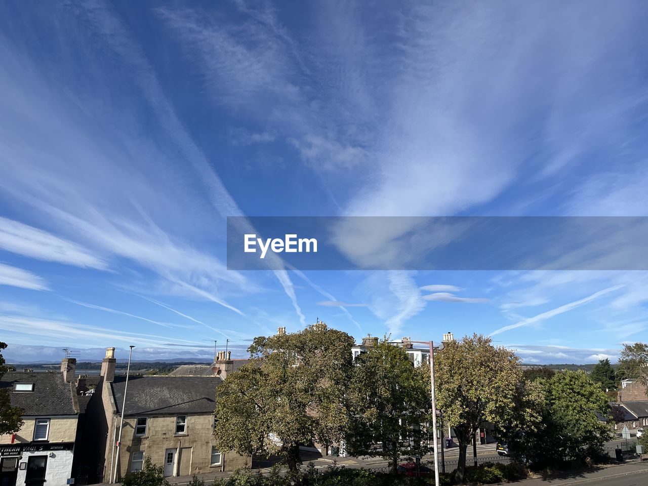 sky, tree, architecture, cloud, built structure, plant, building exterior, nature, city, building, blue, residential area, road, no people, street, residential district, day, house, outdoors, horizon, cityscape, transportation, sunlight, motor vehicle, car