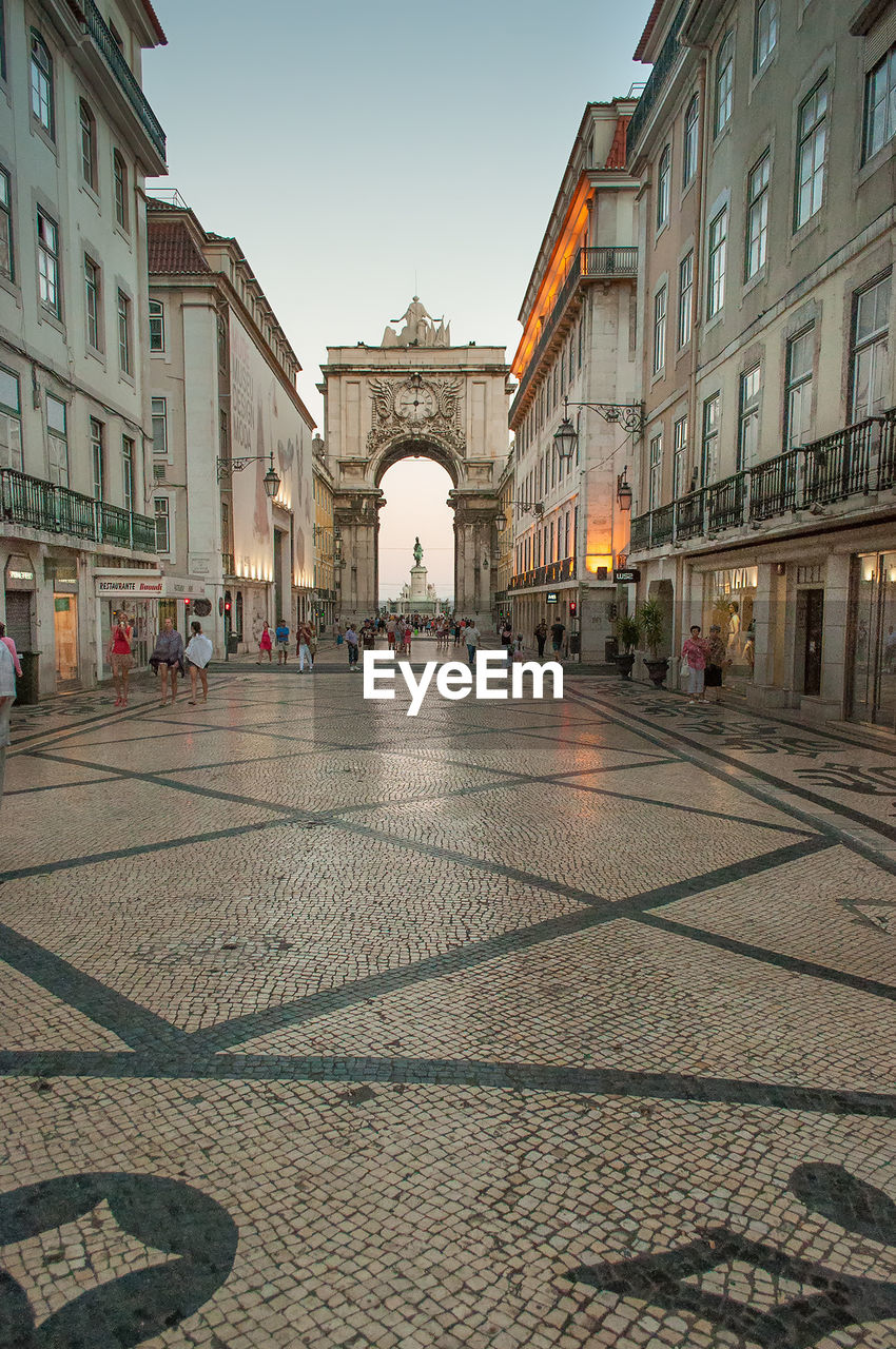 People walking on street amidst buildings at praca do comercio