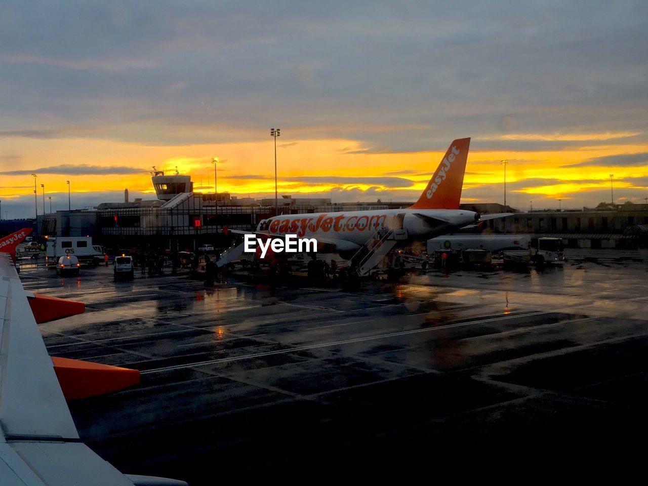 Airplanes on runway against sky during sunset