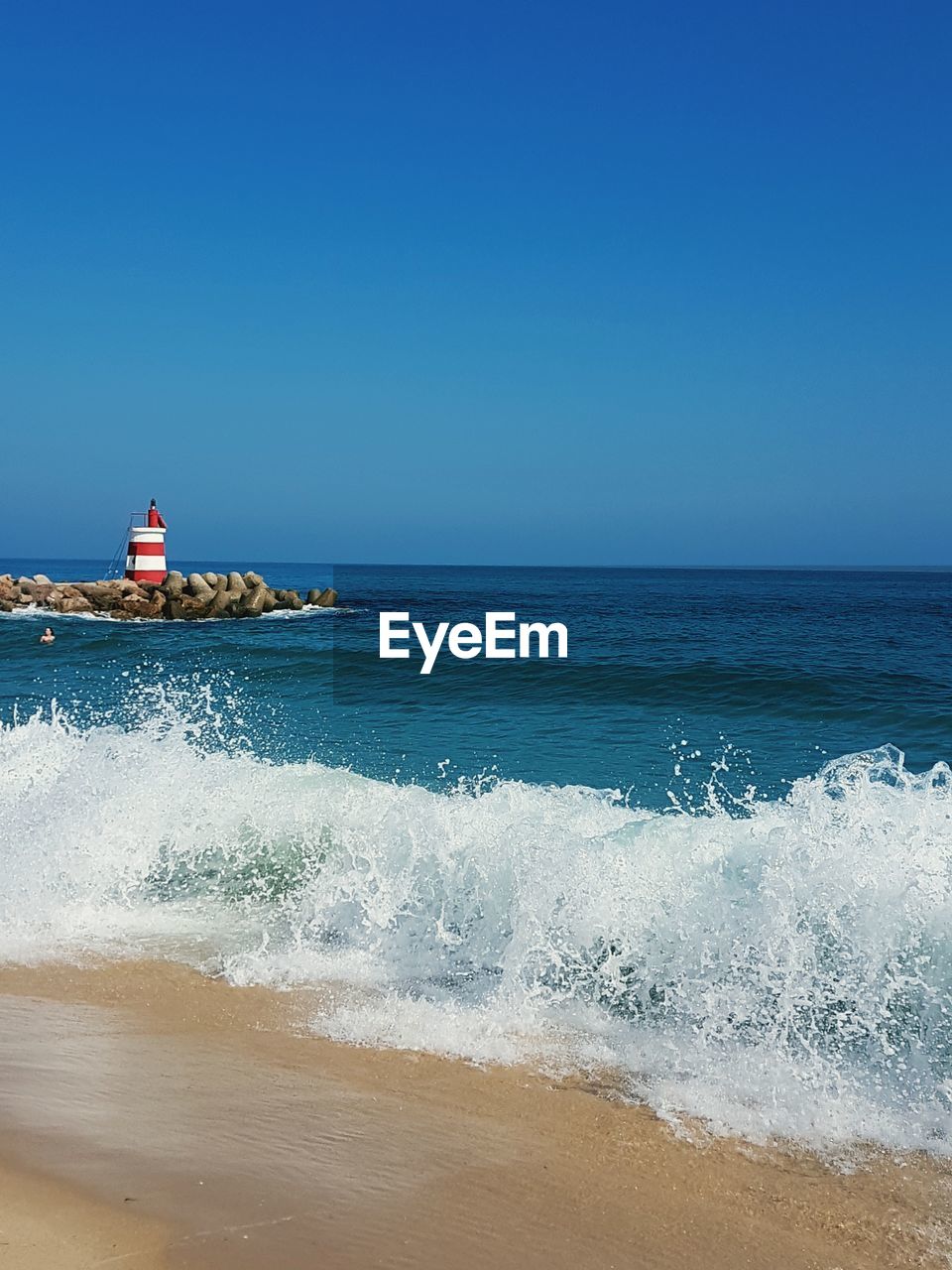 Waves rushing towards shore against clear sky