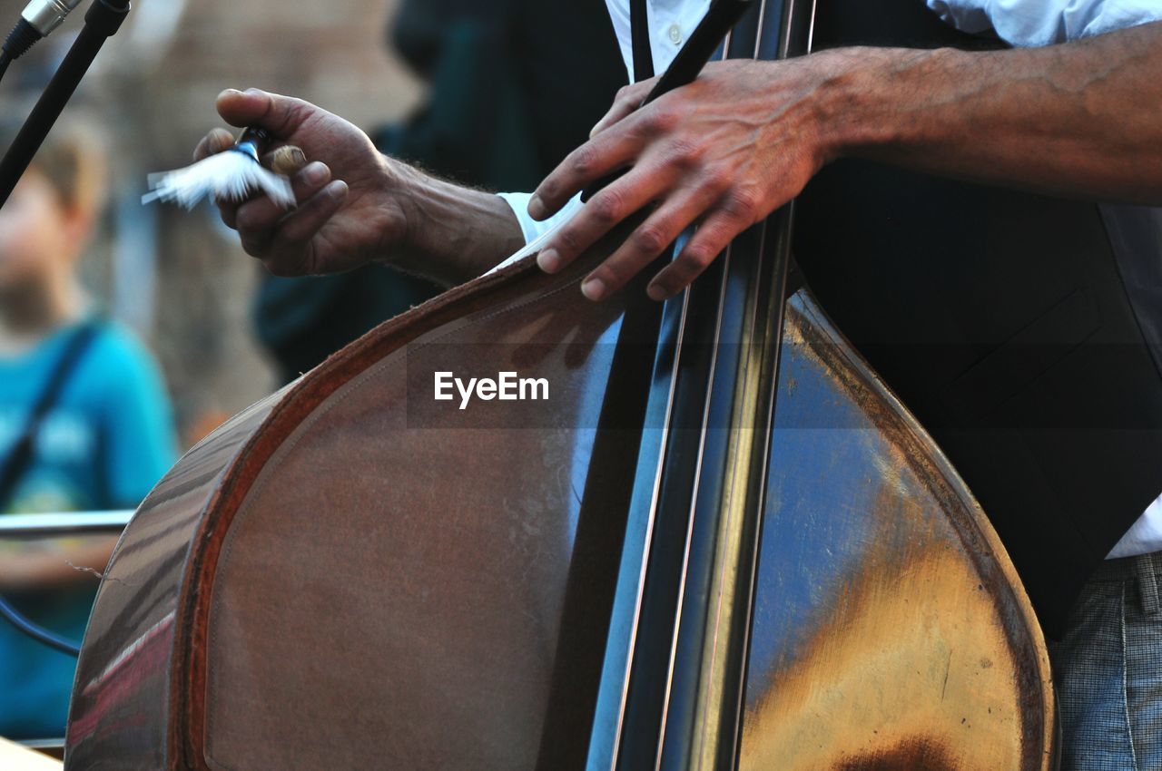 Midsection of man holding double bass