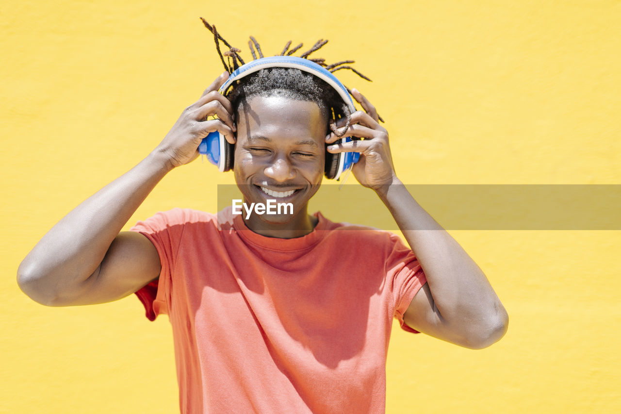 Cheerful black guy putting on headphones
