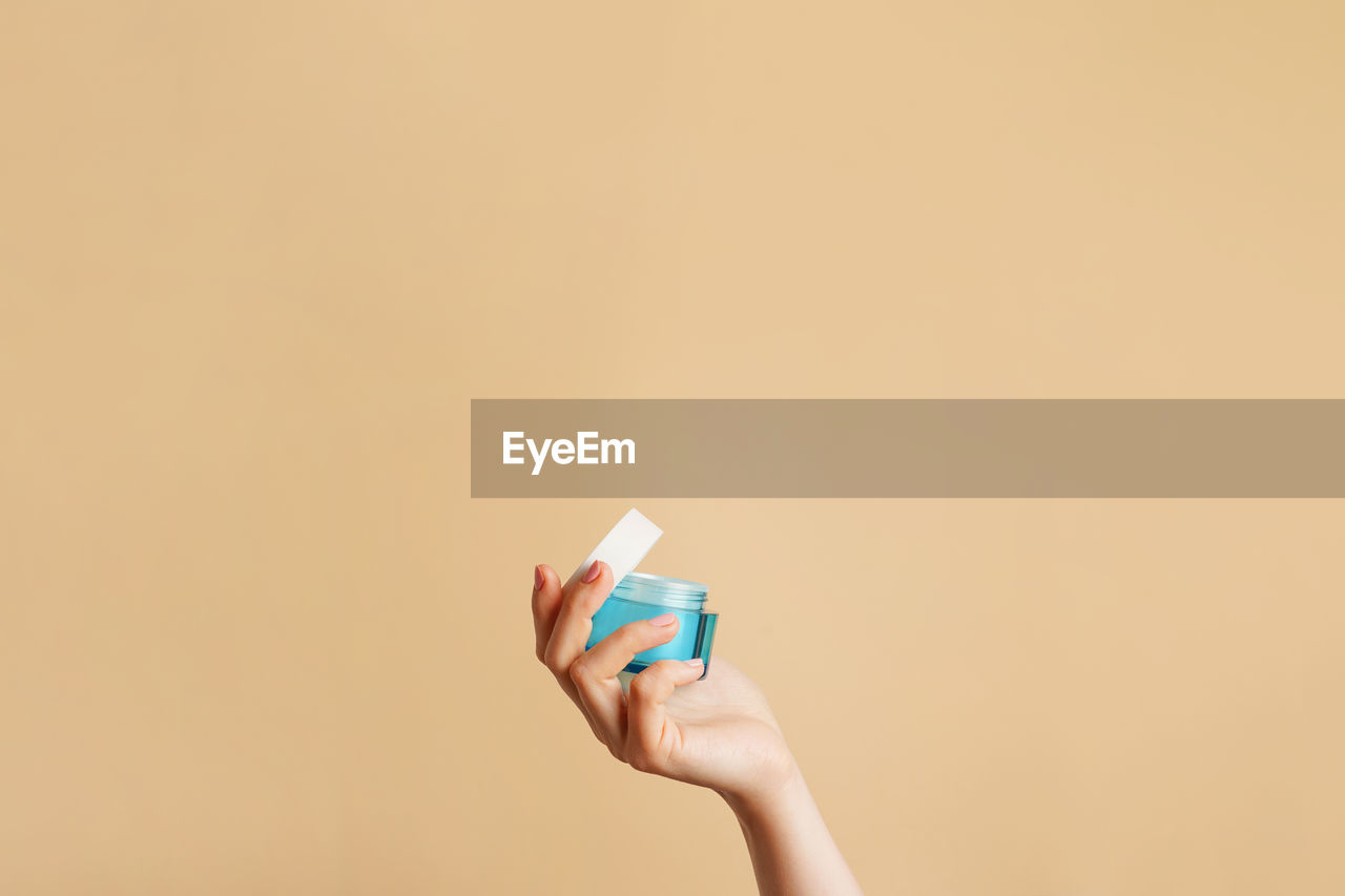 cropped hand of woman holding condom against yellow background