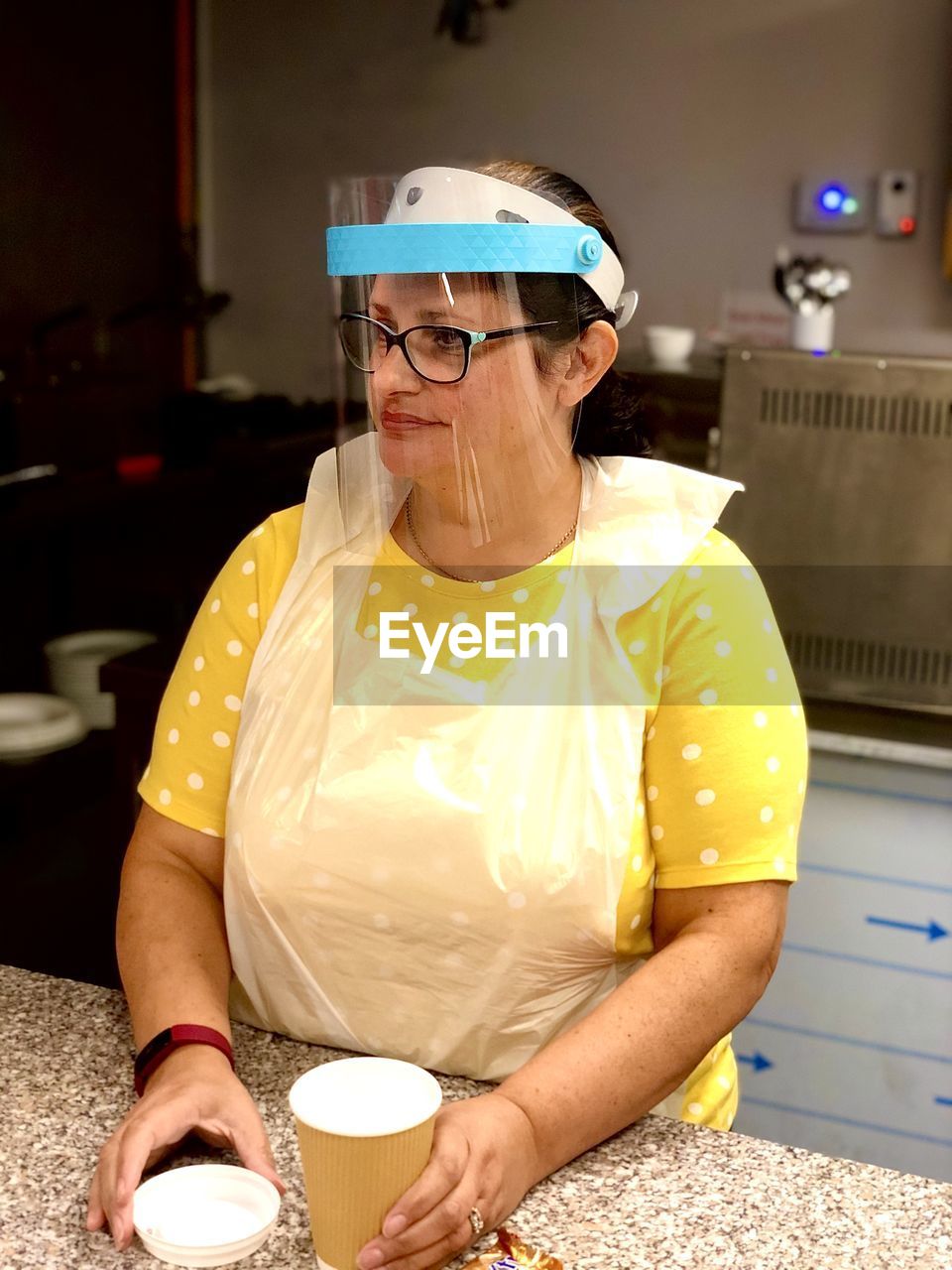 Portrait of woman serving in a cafe  wearing face shield