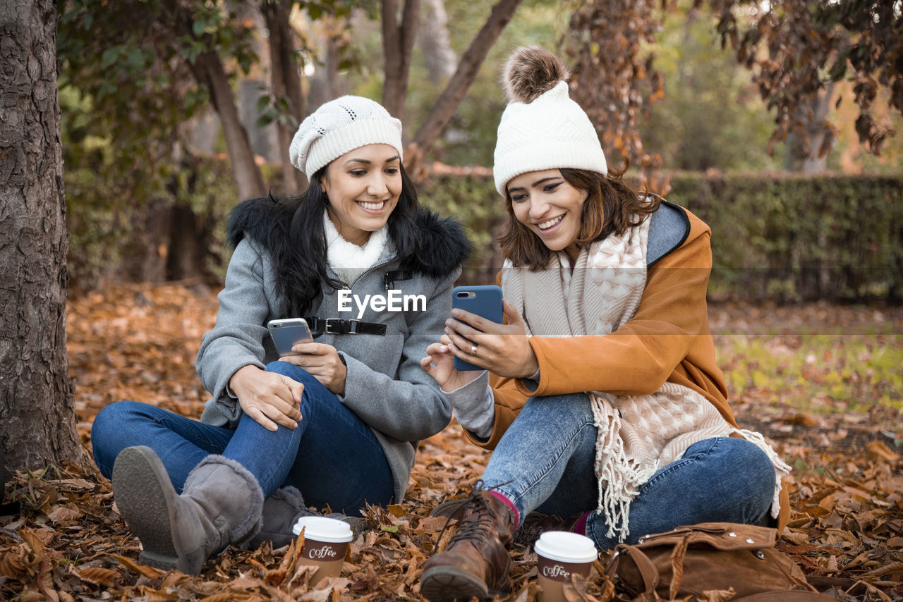 Two old girl friends looking at the smartphone screen together. close up of two old girl friends and the park background in the fall.