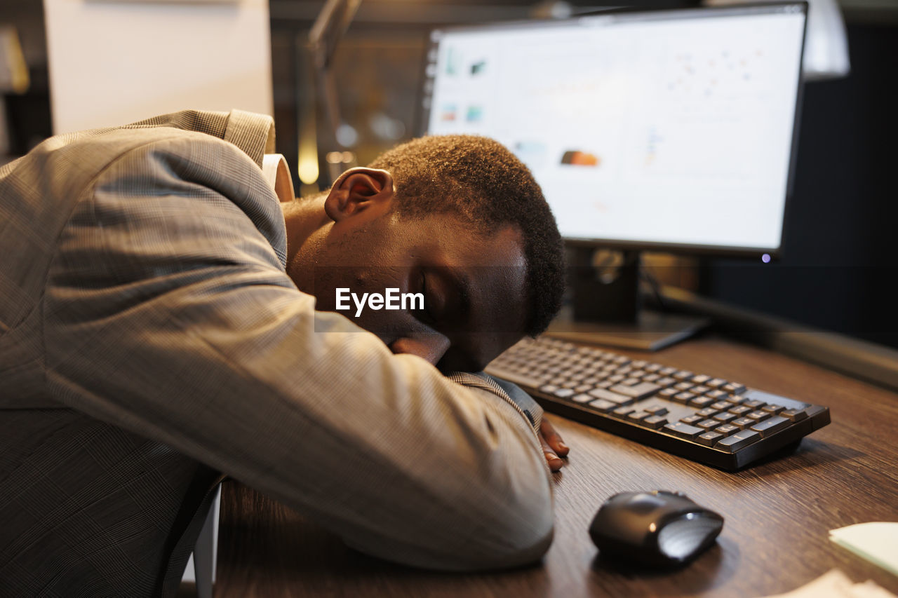 side view of man working on table in office