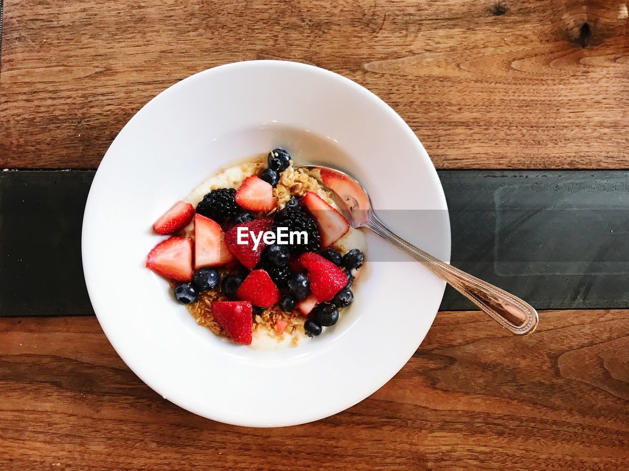 High angle view of fruits with granola breakfast in bowl on a wooden table