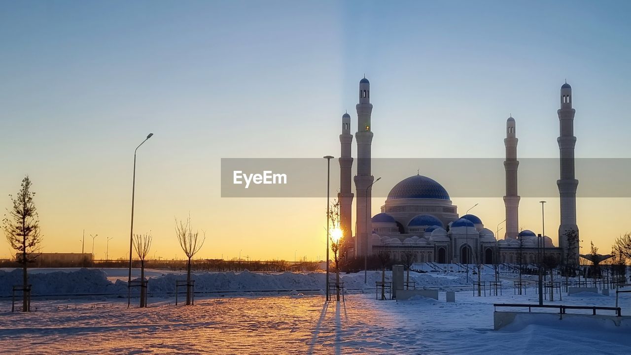 sky, snow, evening, sunset, place of worship, architecture, nature, winter, religion, built structure, dome, dusk, travel destinations, building exterior, reflection, cold temperature, travel, environment, no people, belief, clear sky, sun, water, beauty in nature, landmark, sunlight, scenics - nature, outdoors, spirituality, landscape, twilight, building