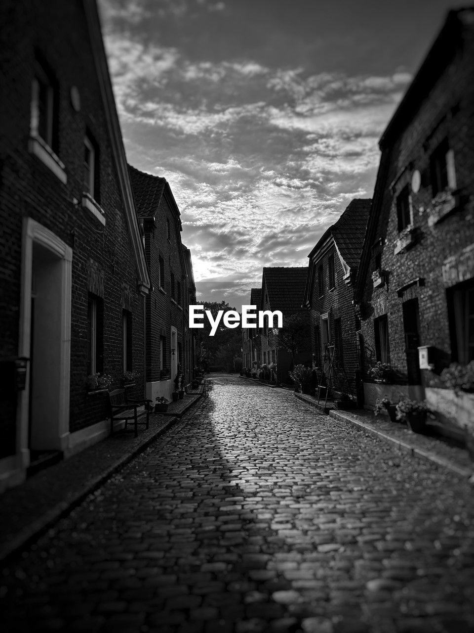 architecture, darkness, building exterior, built structure, black, street, road, alley, sky, black and white, building, monochrome, city, cloud, cobblestone, light, monochrome photography, white, the way forward, residential district, no people, urban area, night, nature, footpath, diminishing perspective, evening, infrastructure, outdoors, house, lane, stone, vanishing point