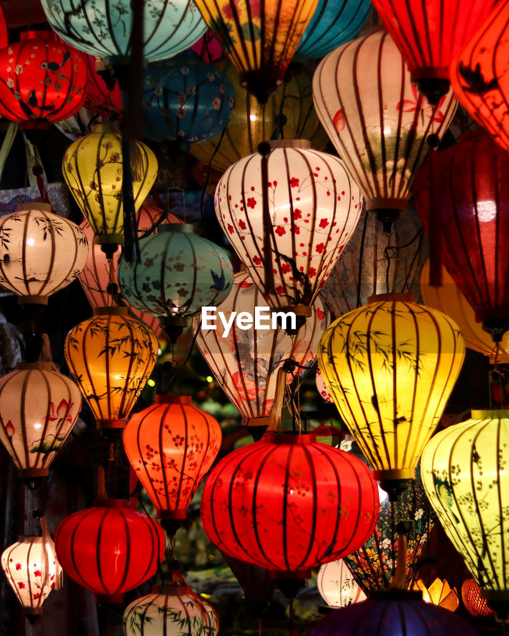 LOW ANGLE VIEW OF ILLUMINATED LANTERNS HANGING AT MARKET