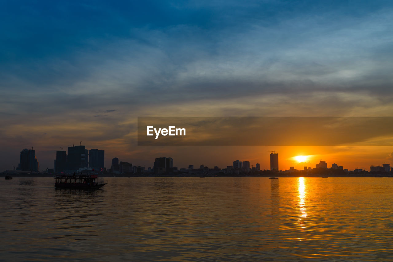 SCENIC VIEW OF SEA AGAINST BUILDINGS DURING SUNSET