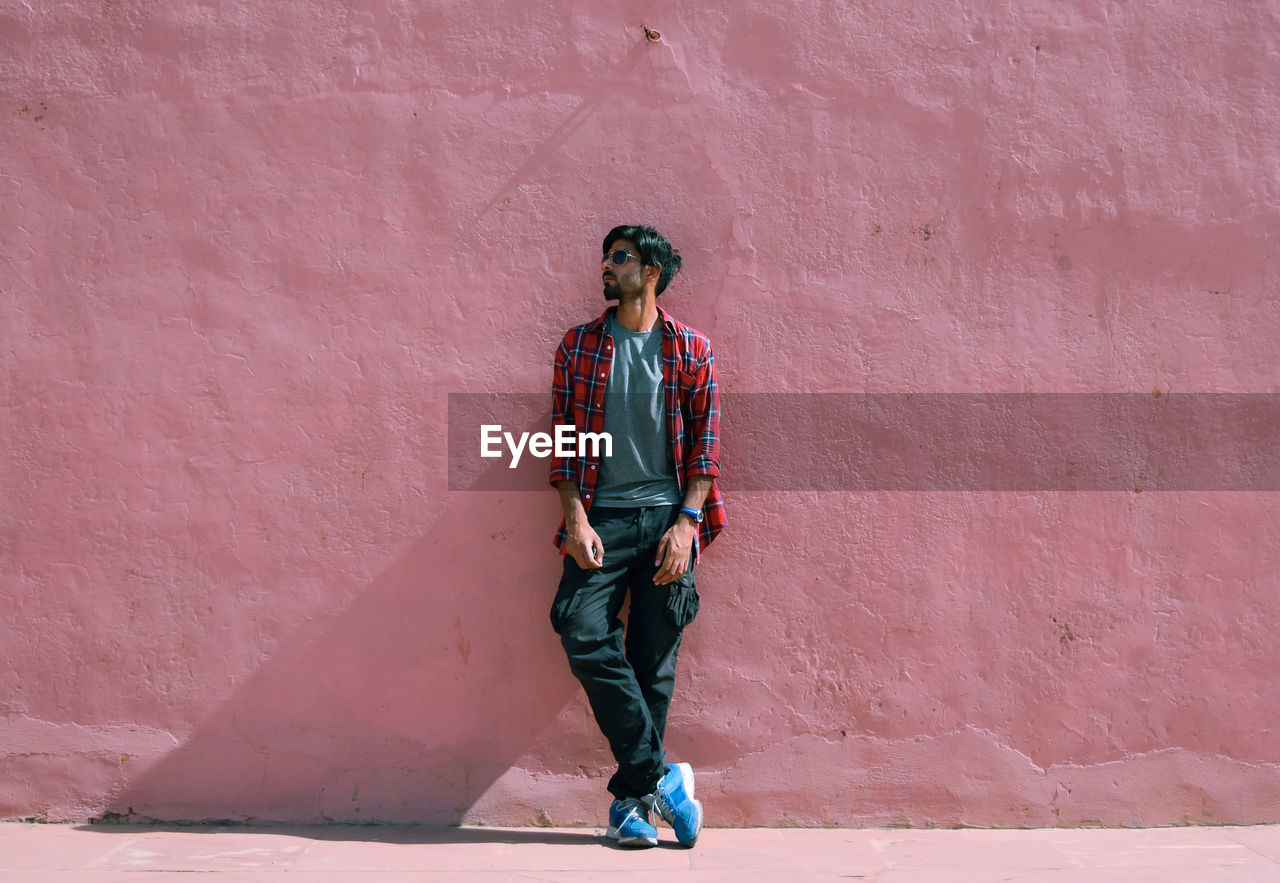 Fashionable man standing against pink wall