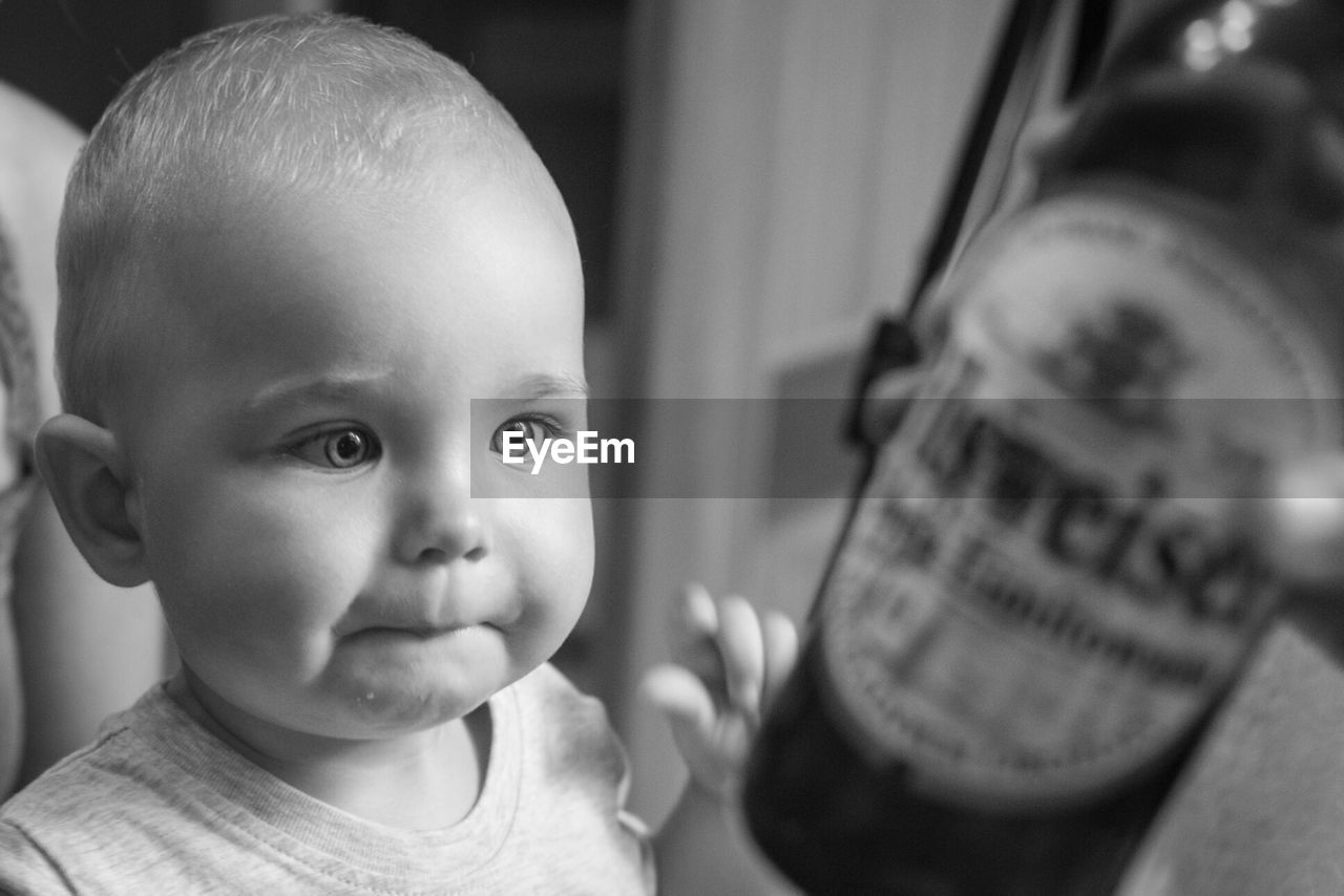Baby looking at beer bottle