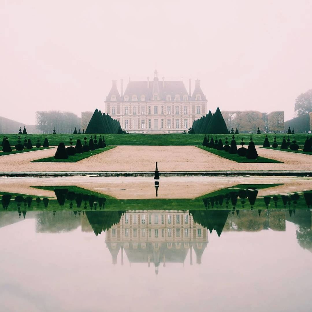 Castle reflecting on pond against sky during foggy weather