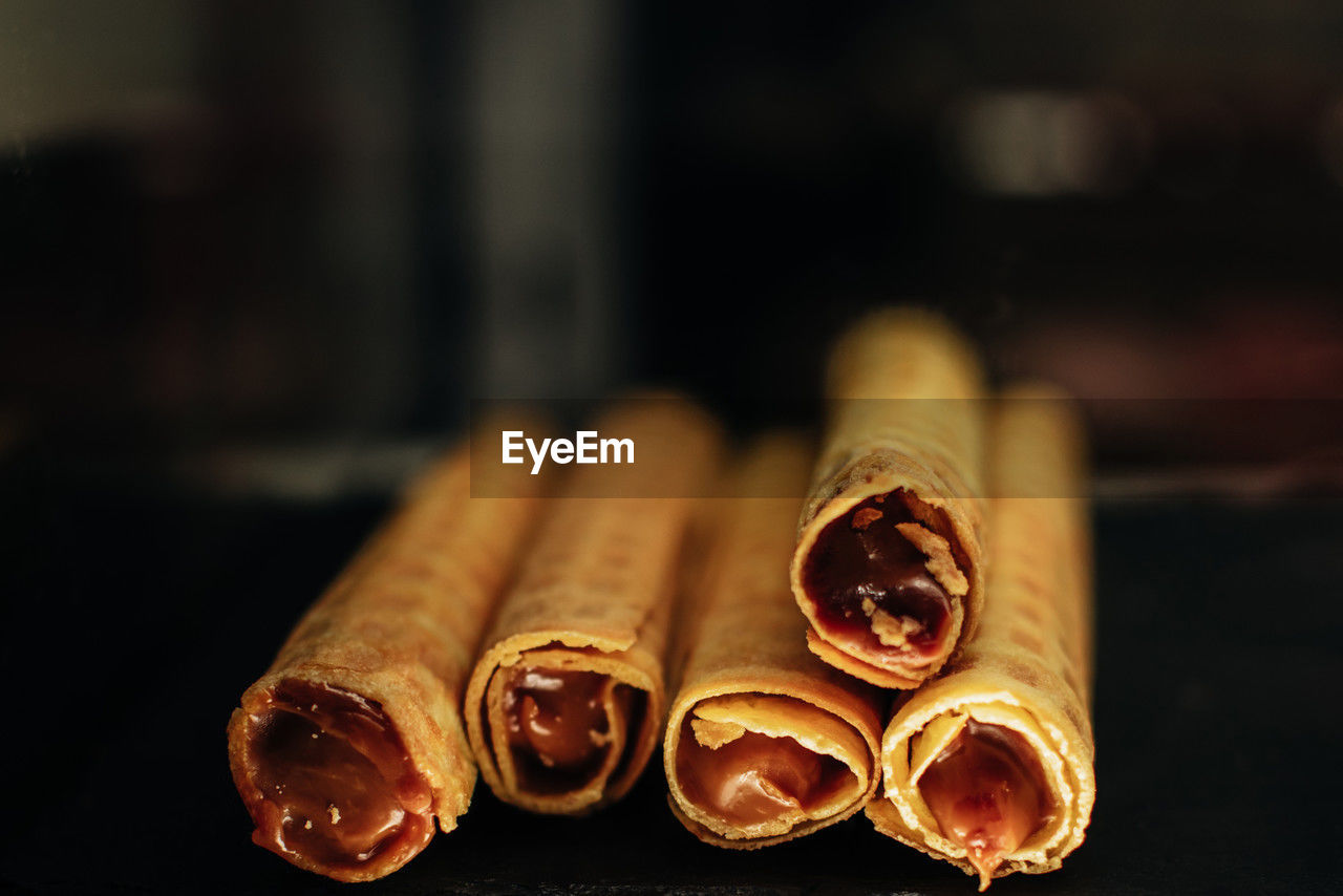 Sweet wafer rolls with chocolate condensed milk on dark background