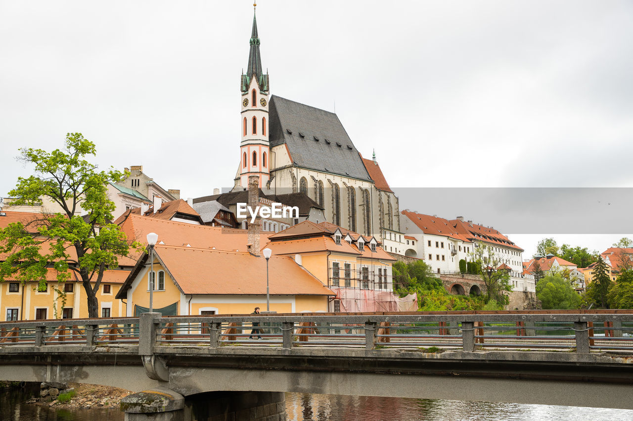 BRIDGE OVER RIVER AMIDST BUILDINGS AGAINST SKY IN CITY