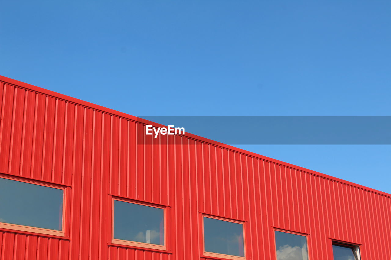 Low angle view of red building against clear blue sky