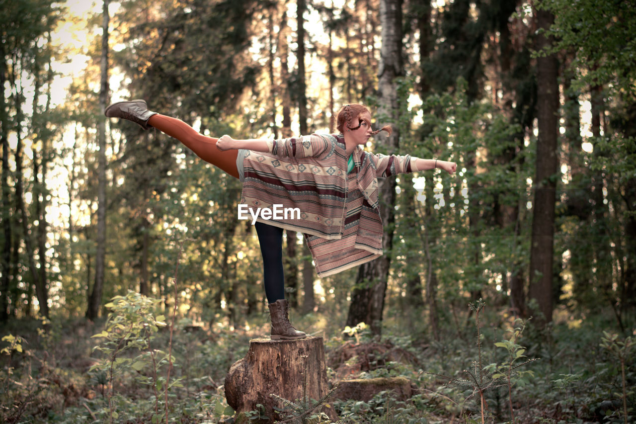 Woman standing on tree stump in forest