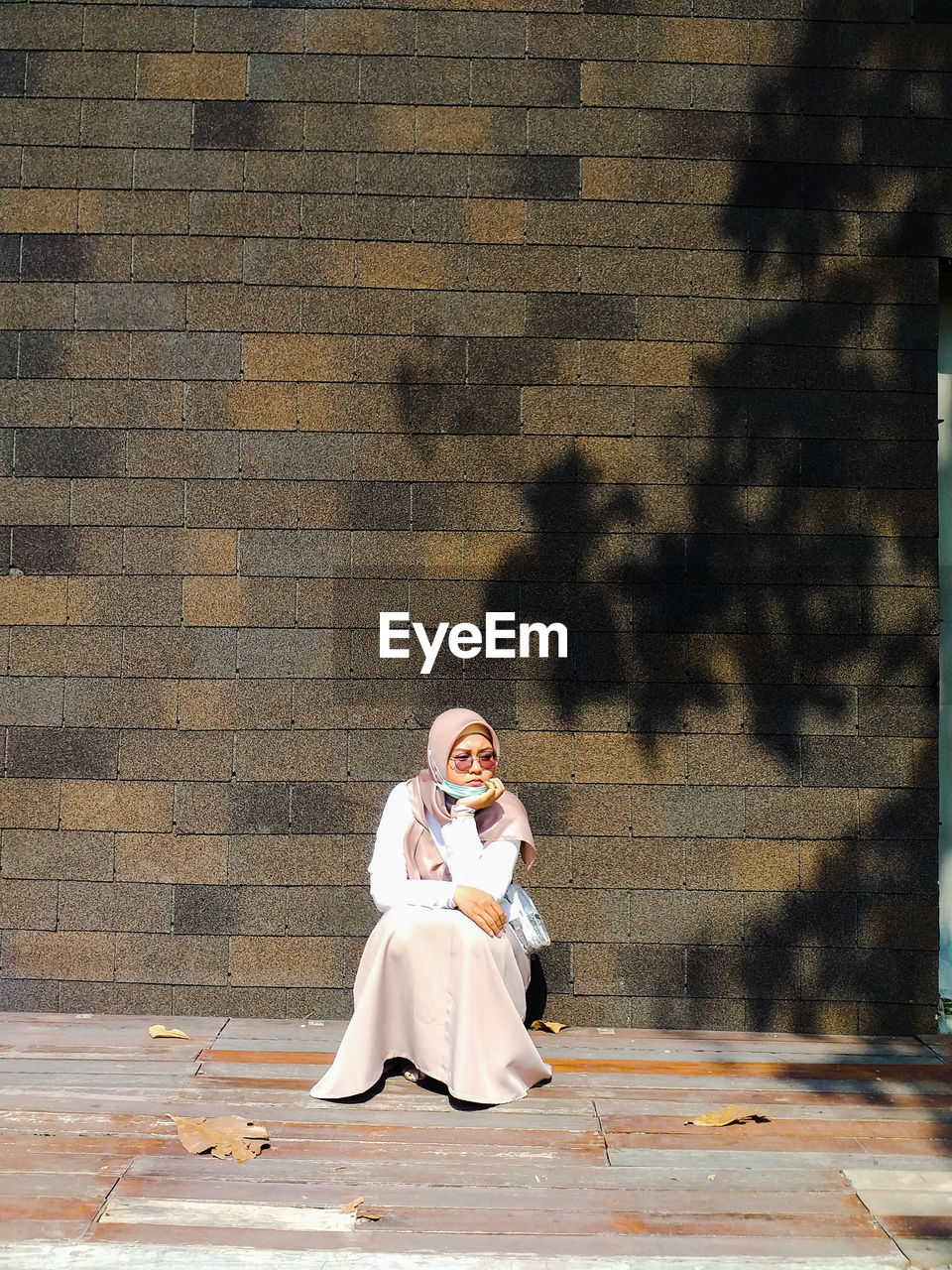 Full length of woman sitting against wall