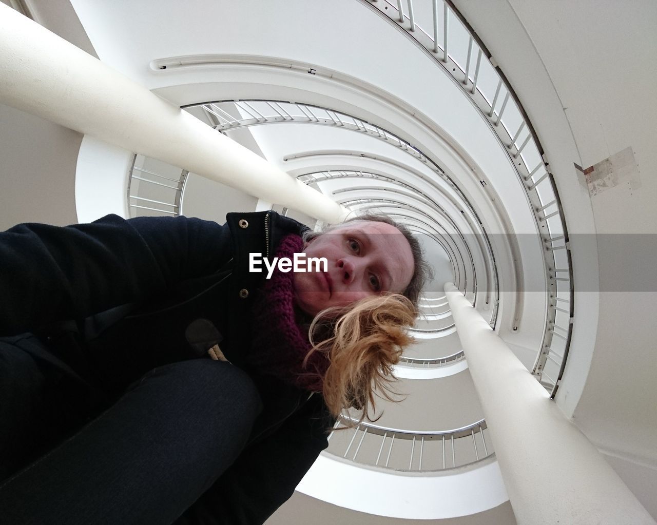 Directly below portrait of woman against spiral staircase