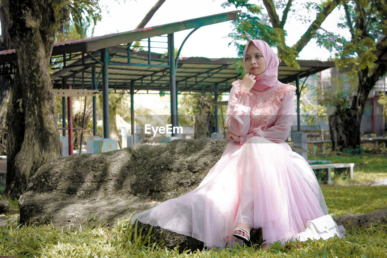 Woman with pink umbrella against trees