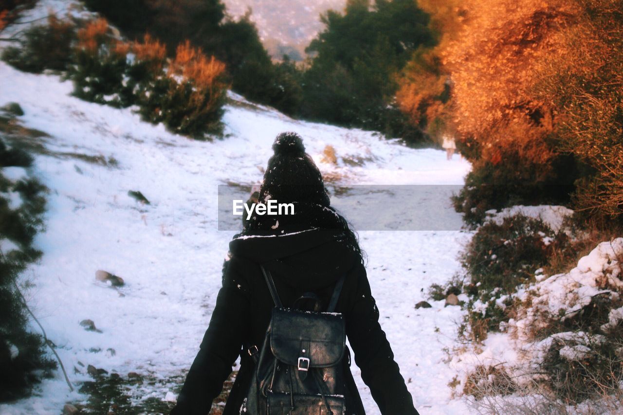 Rear view of woman wearing warm clothing while standing on snowy field