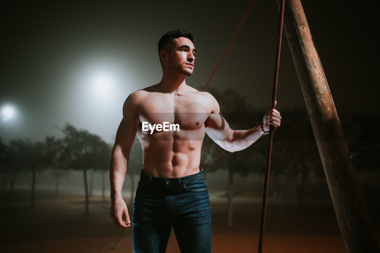 Shirtless muscular man on the street on a foggy night