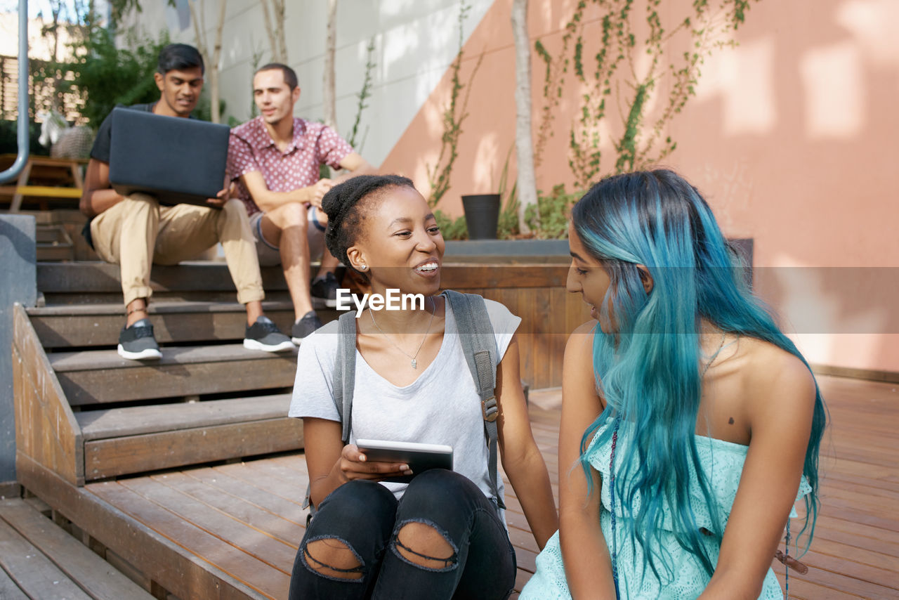 Cheerful friends talking while sitting outdoors