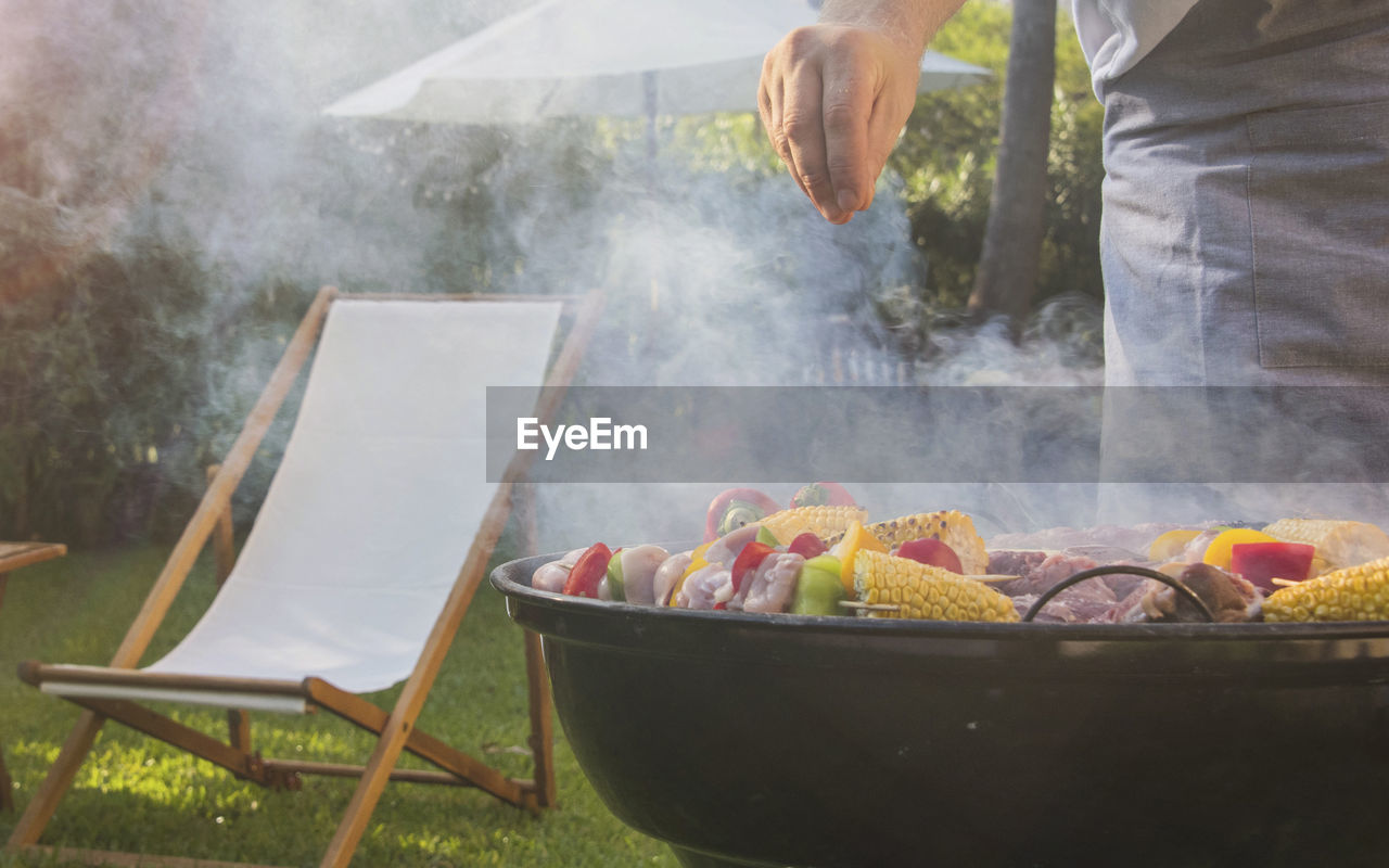 midsection of man preparing food on fire