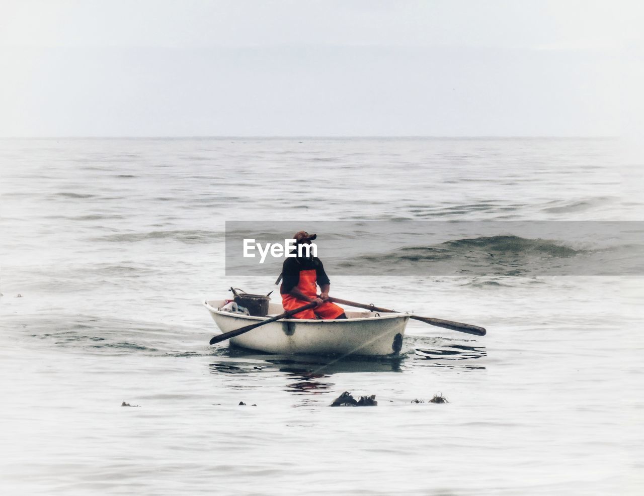 MAN IN BOAT AT SEA AGAINST SKY