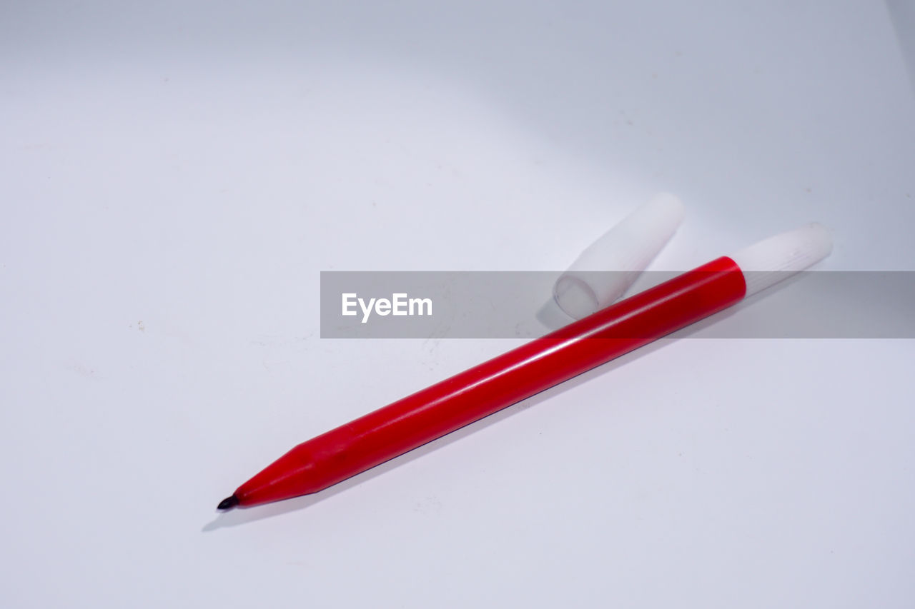 CLOSE-UP OF RED COLORED PENCILS AGAINST WHITE BACKGROUND