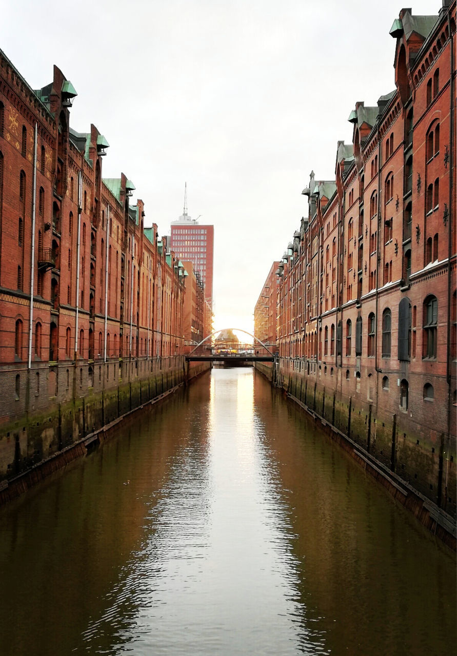 Canal amidst buildings in city against sky